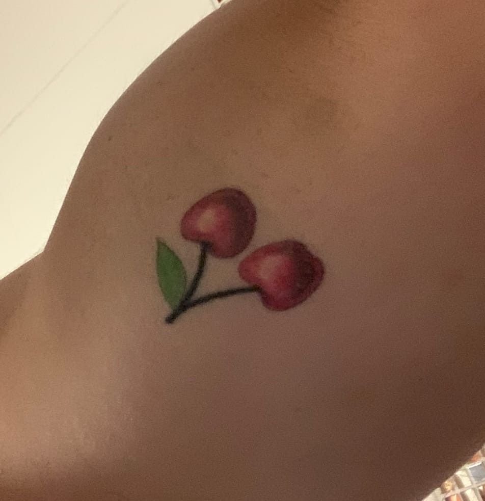 Deux cerises rouges et leur feuille verte, tatouées en couleur.