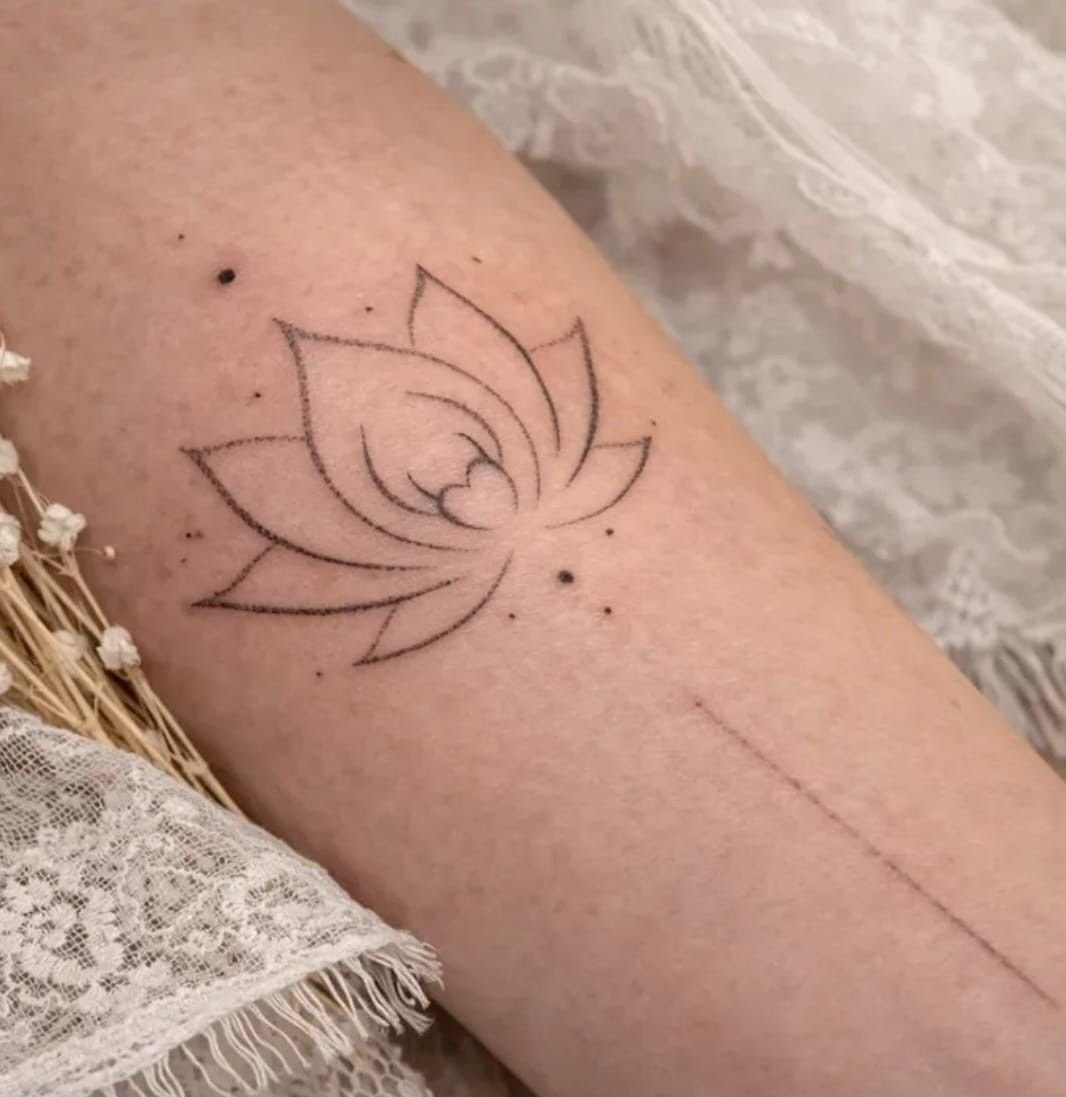 Fleur de lotus en trait fin, entourée de points et prolongée d’une ligne pointillée.