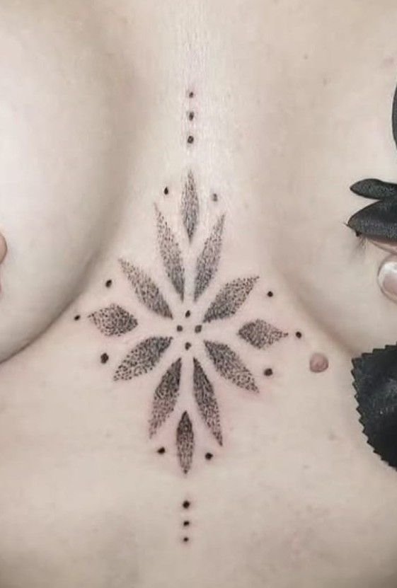 Ornement en étoile à huit branches, ombré en points et prolongé de petits points, sur le sternum.