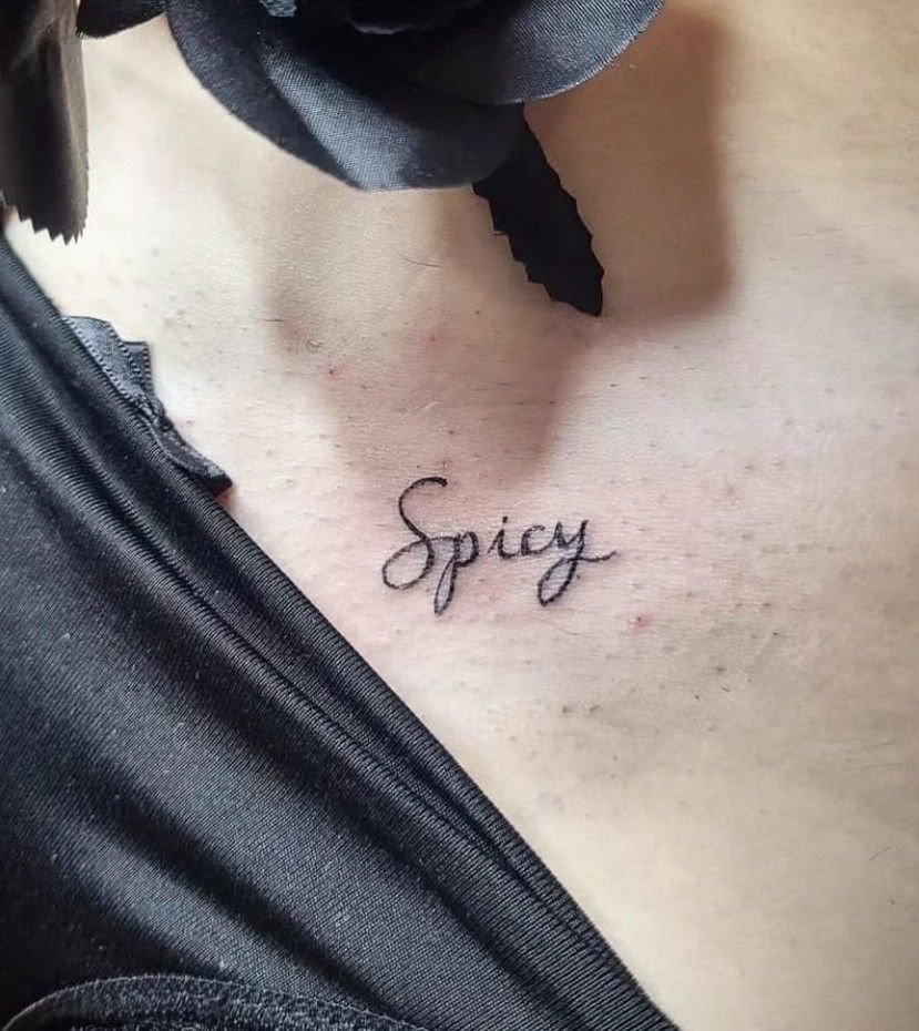 Le mot « Spicy » en écriture fine, sous la clavicule.